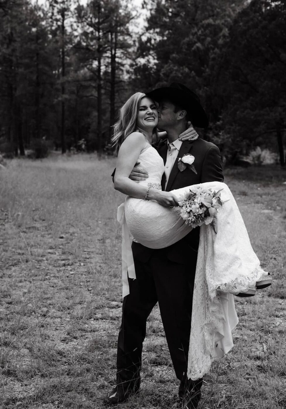 Groom carrying bride through the forest